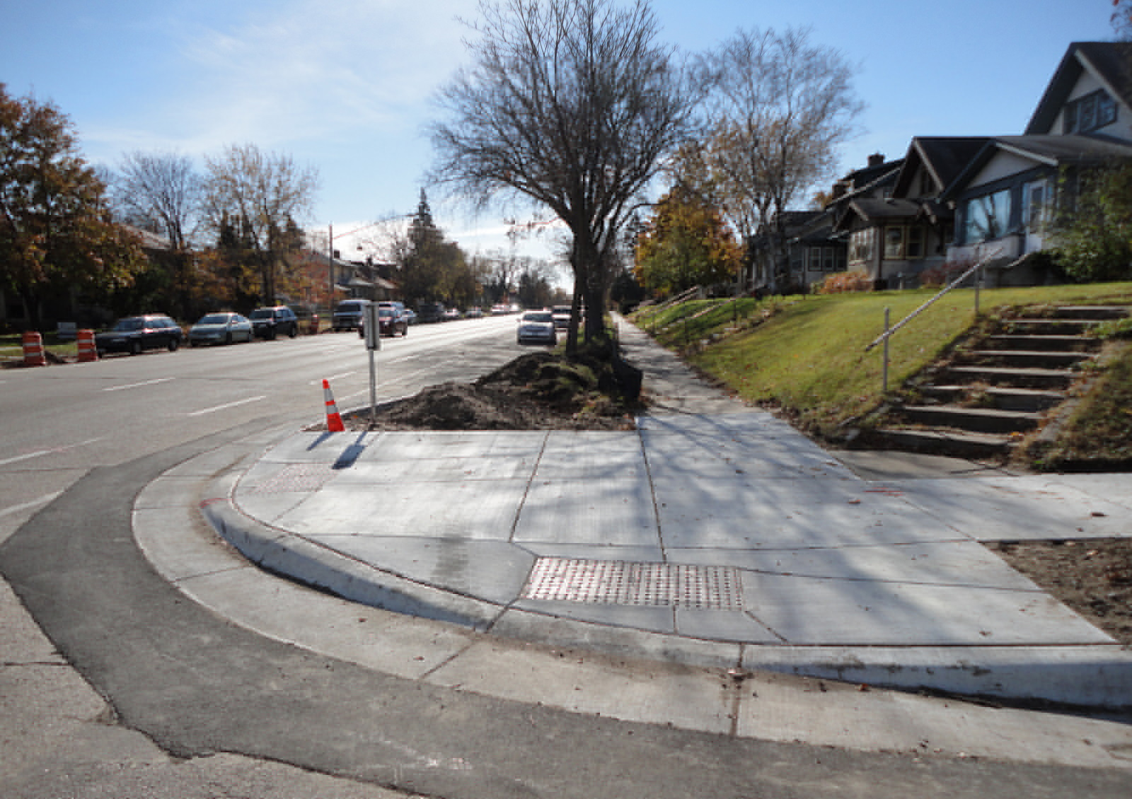 The corner of an intersection where two sidewalks meet. The sidewalks each have curb cuts built into them, which look like ramps going into the street.